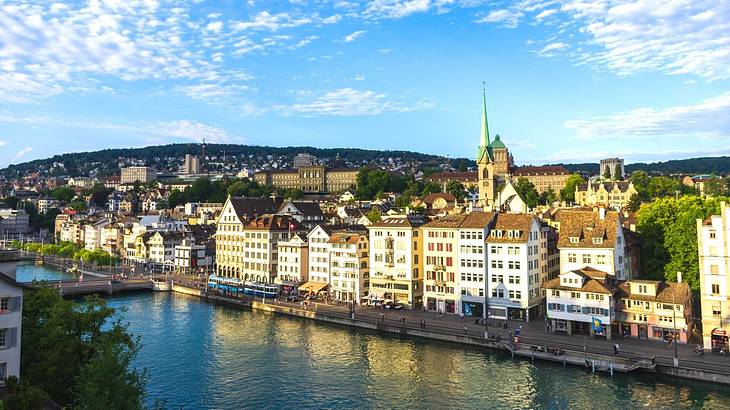 A town with historical buildings overlooking water under a partly cloudy sky