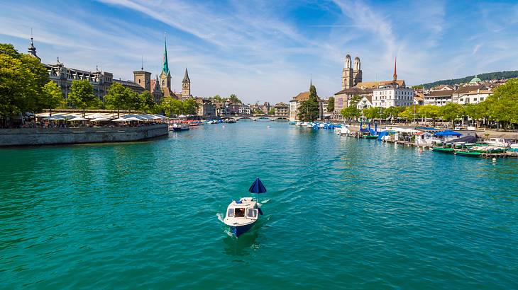 A boat on blue water with a bridge behind it connecting two parts of the city