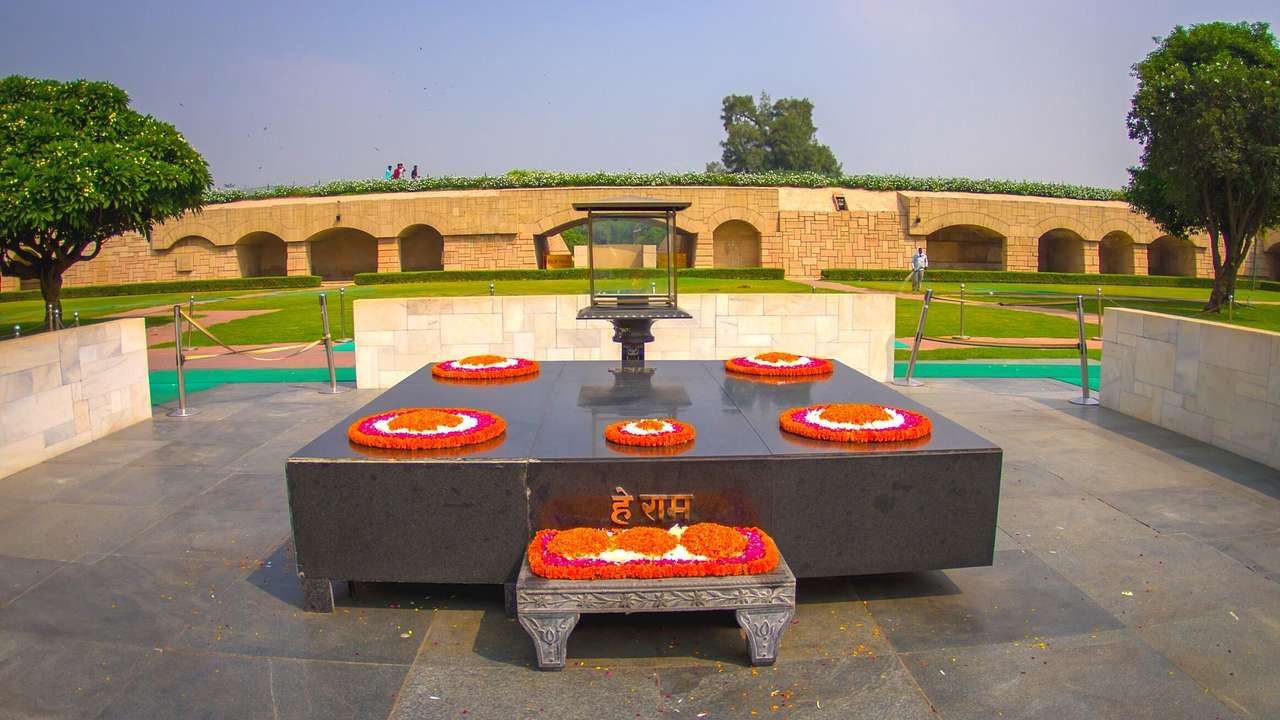 A black monument with orange flower decorations surrounded by grass and trees