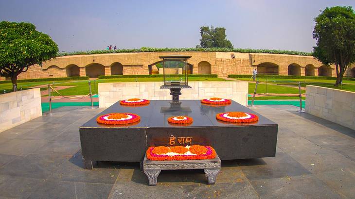 A black monument with orange flower decorations surrounded by grass and trees