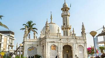 The exterior of a white mosque with palm trees next to it