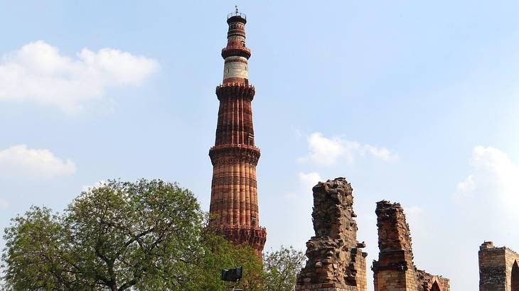 A tall ancient tower surrounded by trees and other ancient ruins