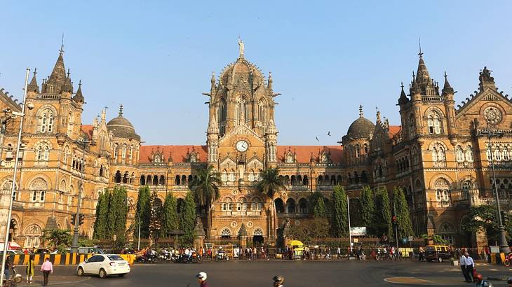 A large historical building next to a busy street with tourists and traffic on it