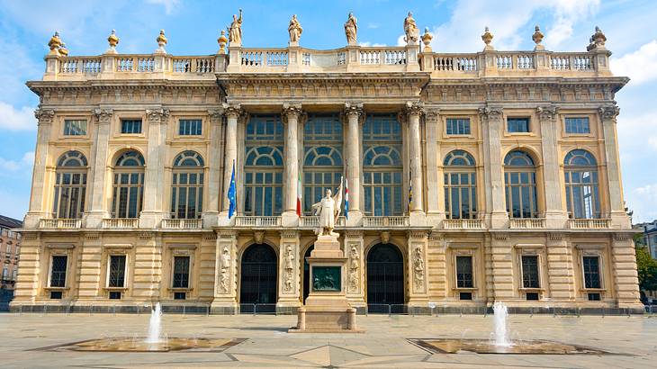 A historical building with columns and arched windows and a statue outside