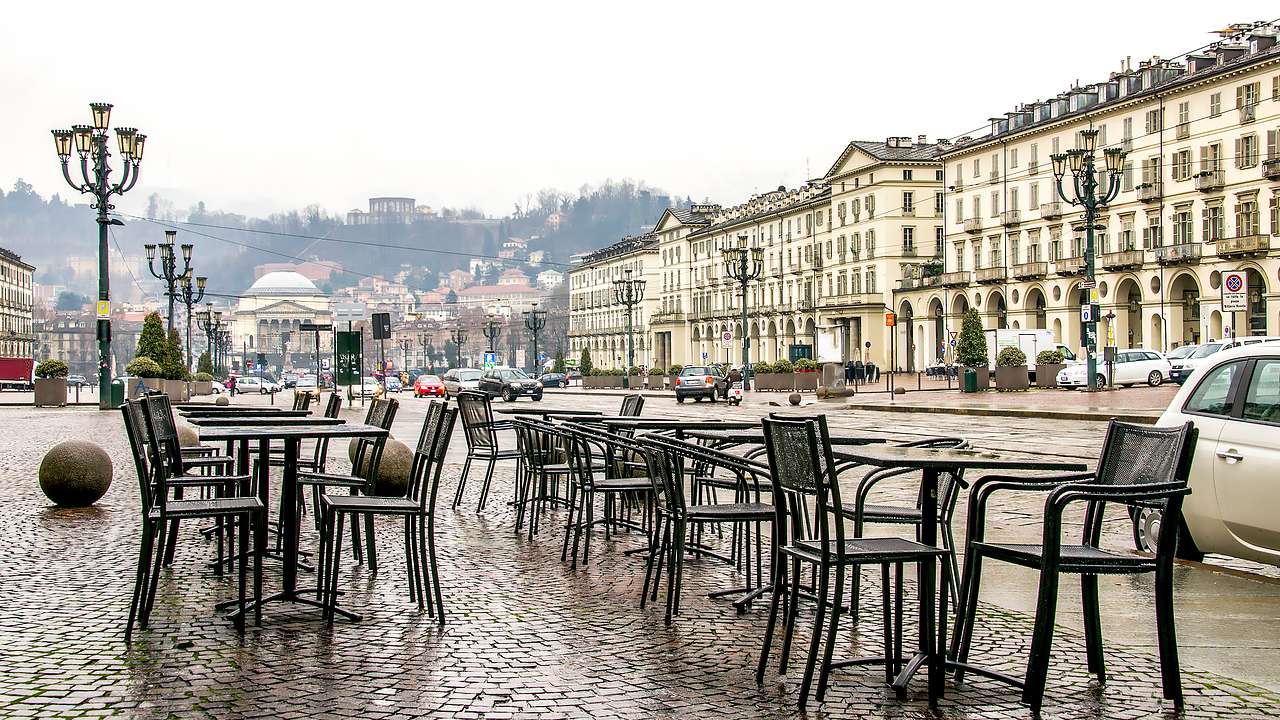 An outdoor patio on the street with tables next to historical buildings