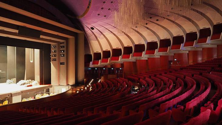 Red velvet seats facing a stage with a modern wooden ceiling