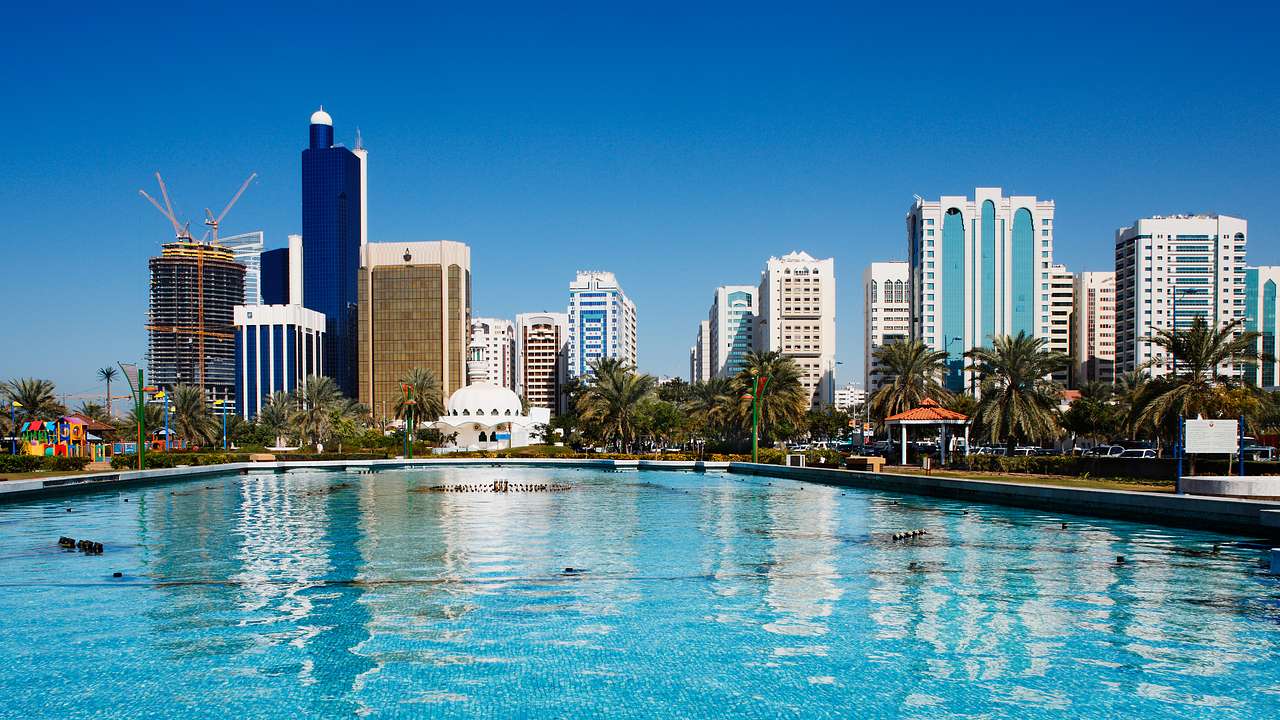 A skyline with modern tall buildings overlooking a pool with blue water