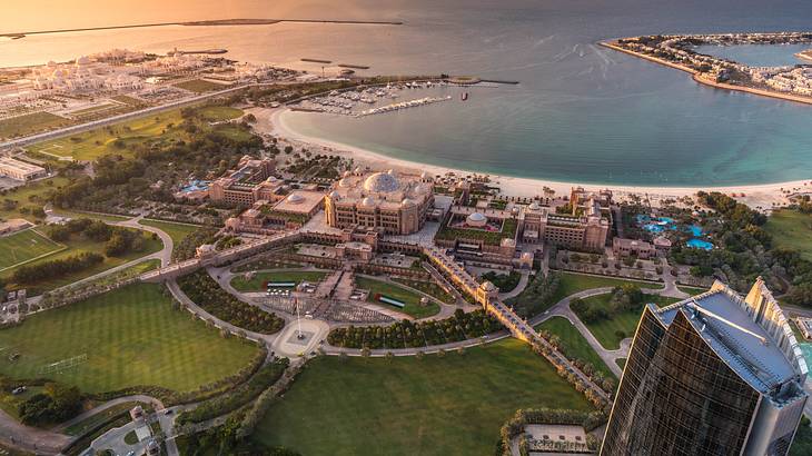 A bird's eye view of modern buildings surrounded by greenery and a beach