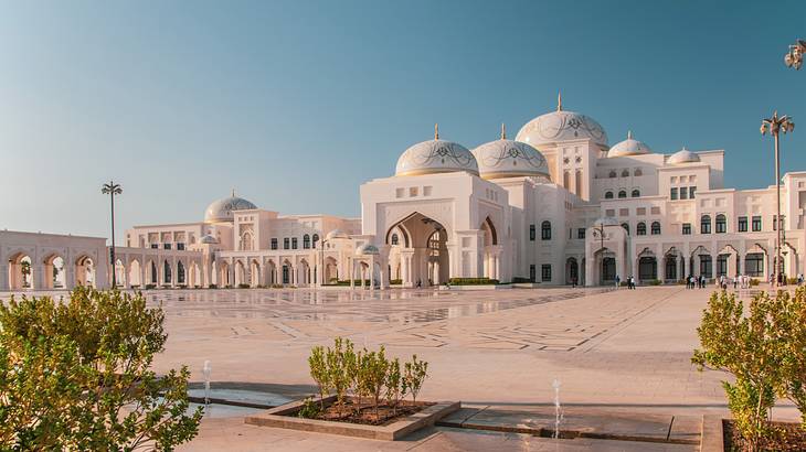 A white marble palace with arched columns and several domes under a clear sky