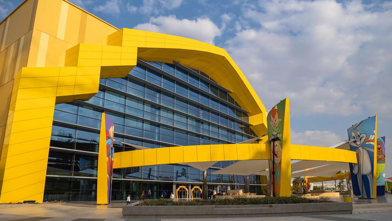 A yellow gate with cartoon characters in front of a yellow building with a glass wall