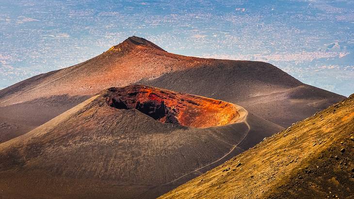 An orange volcanic crater on a brown mountain
