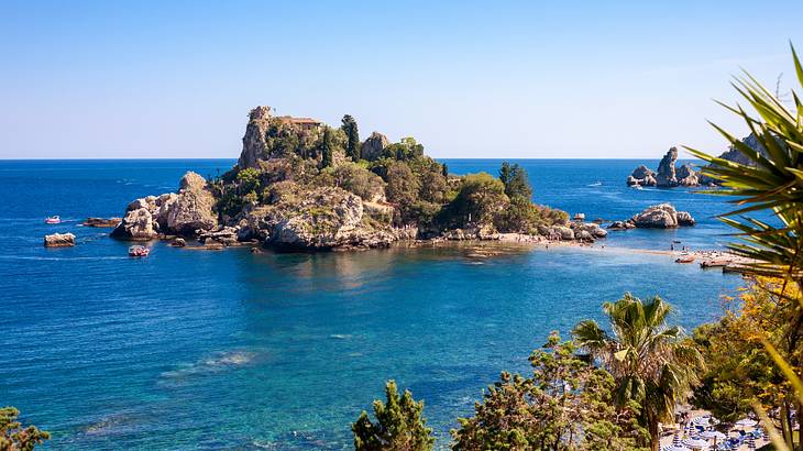 A small island with rugged terrain and shrubbery surrounded by blue water