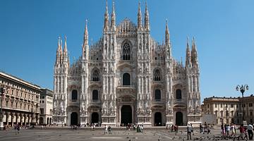 A gray cathedral building with Italian gothic architecture under a clear blue sky