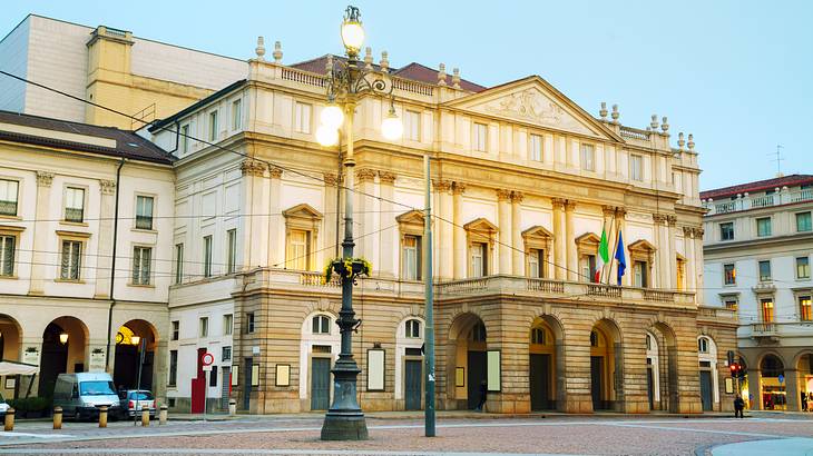 A white neoclassical building with arches on its entrance and a street in front of it