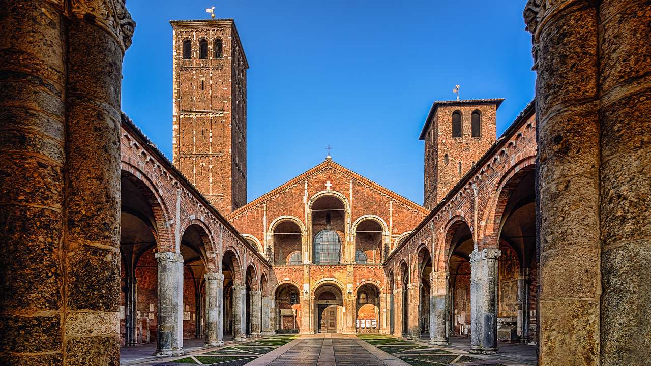 A walkway inside an ancient church with arched columns and two towers