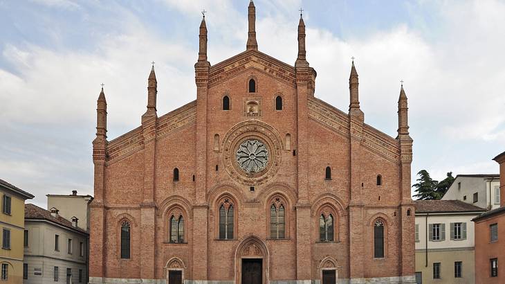 A red brick Baroque-style church building under a fairly cloudy sky