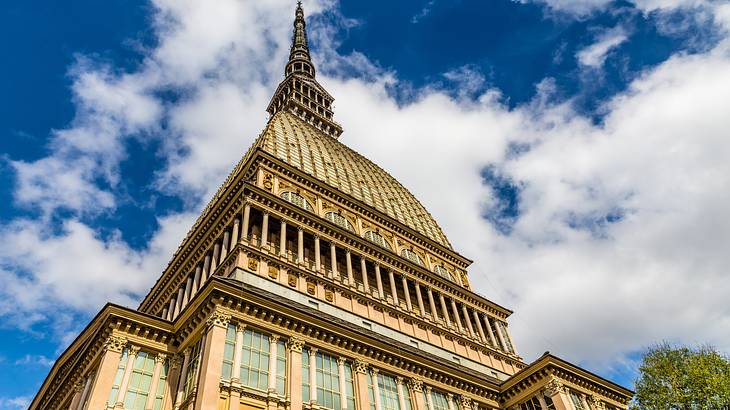 A tall building with a domed roof and a tower on top under a blue sky with clouds