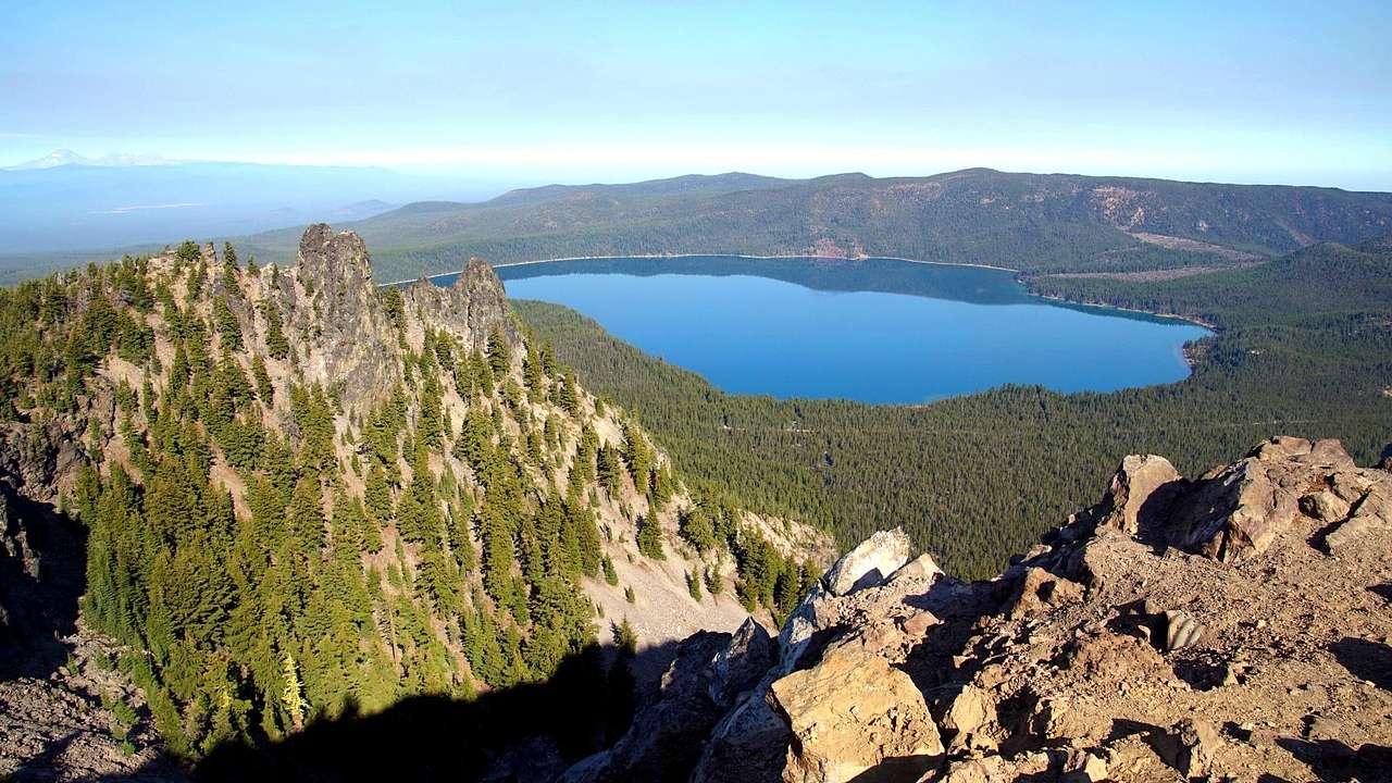 Aerial of a blue lake surrounded by green trees and cliffs covered with trees