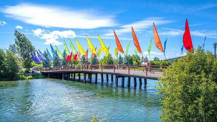A bridge lined with multi-color flags over water under a partly cloudy sky