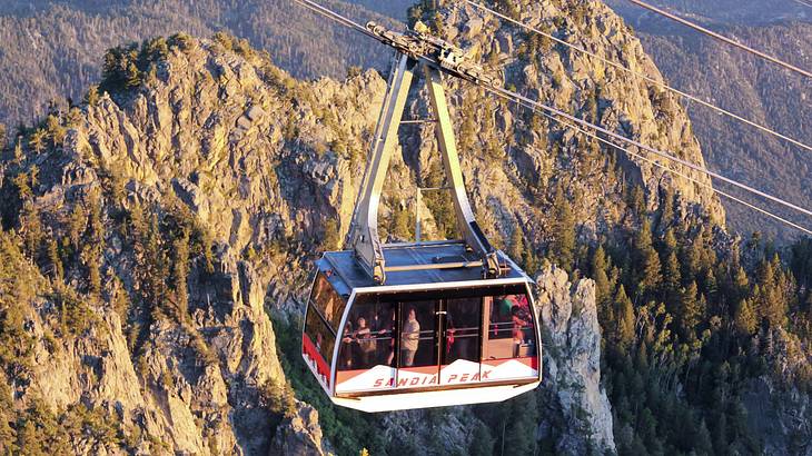 A cable car against tall and rugged mountains covered with green trees A cable car against tall and rugged mountains covered with green trees