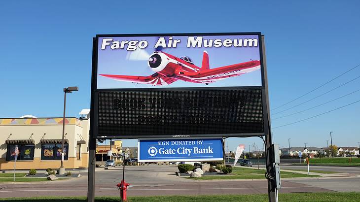 A signboard with a red plane and text of "Fargo Air Museum" at an airport