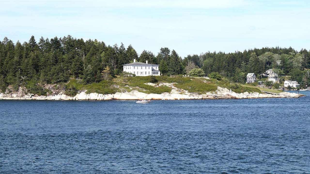 A river in front of an island with trees and a white house on it