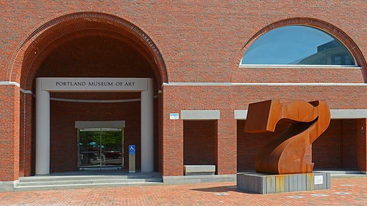 A red brick building with a "Portland Museum of Art" sign and a number seven statue