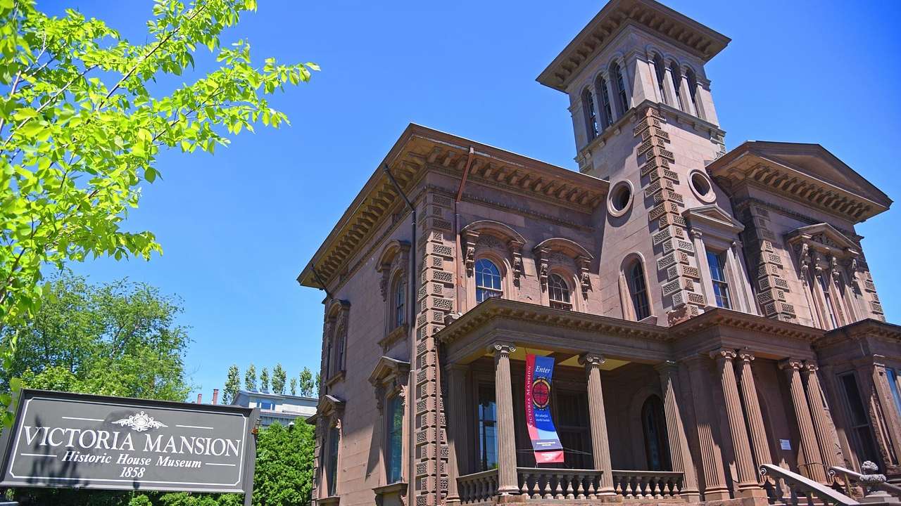An old-fashioned mansion with columns and a tower, and a "Victoria Mansion" sign