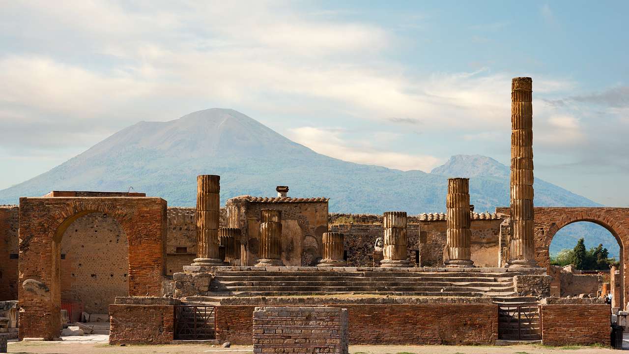 Ruins of an ancient Roman city with a view of a volcano at the back