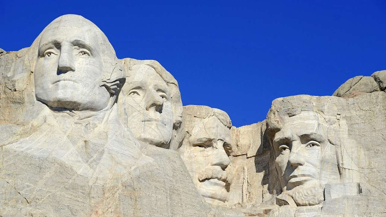 Sculptures of four faces carved into a mountain against a clear blue sky
