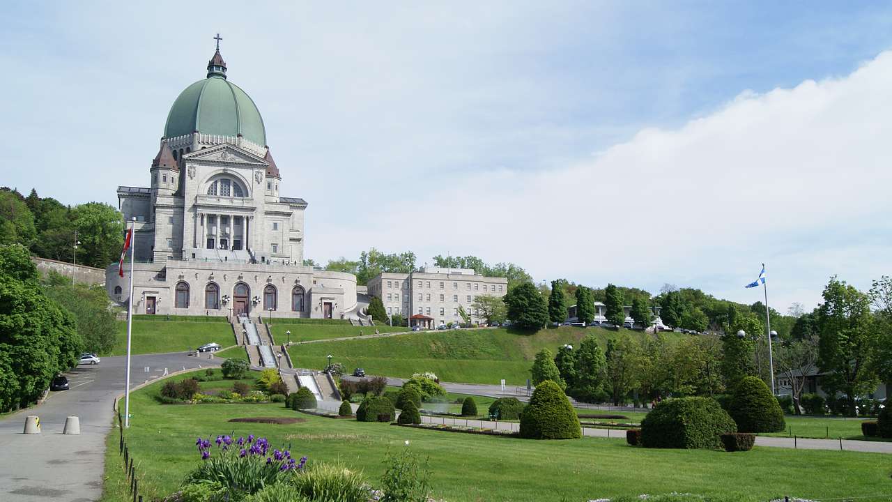A white cathedral with a green dome surrounded by landscaped gardens