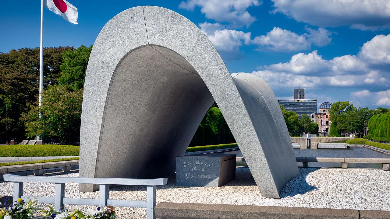 A stone chamber under a saddle-shaped monument with a Japanese flag on its left