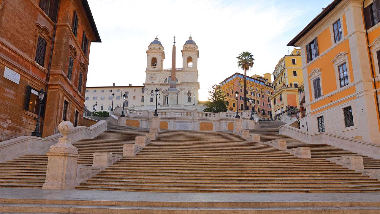 Stairway surrounded by brightly-coloured buildings leading to an obelisk and a church