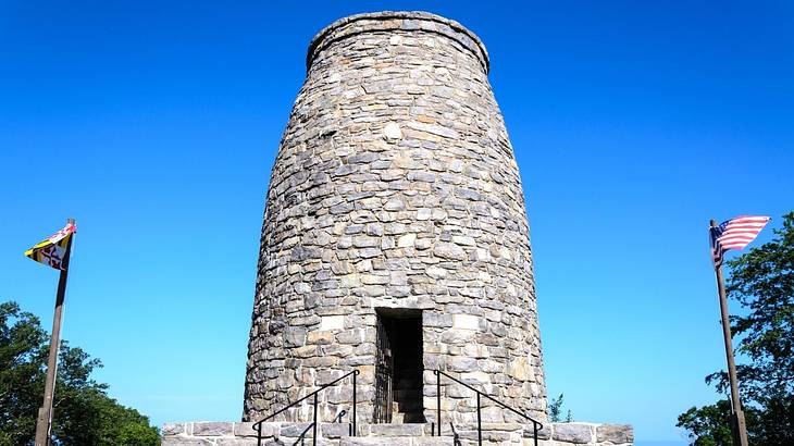 An old stone tower with a flag on each side under a clear blue sky An old stone tower with a flag on each side under a clear blue sky