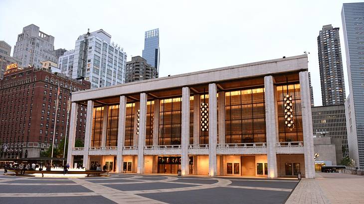 A modern building with columns and floor-to-ceiling glass windows sitting in a square