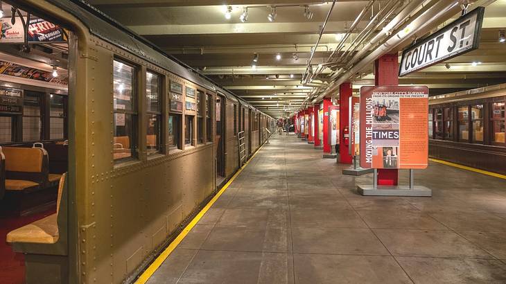 An old-fashioned subway station with a train on the platform and informative signs