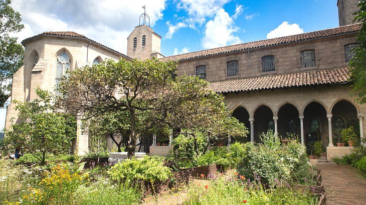 A Spanish-style building with columns and a patio and gardens in front of it