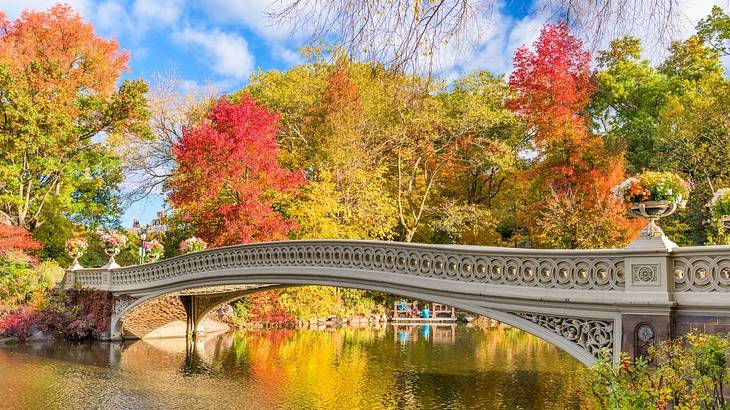 An ornate bridge over a pond surrounded by autumn trees