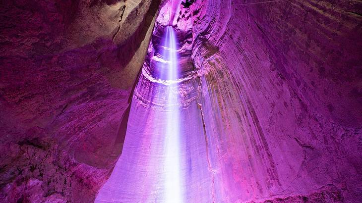 A waterfall flowing into a purple underground cave