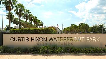 A sign that says "Curtis Hixon Waterfront Park, City of Tampa" next to palm trees