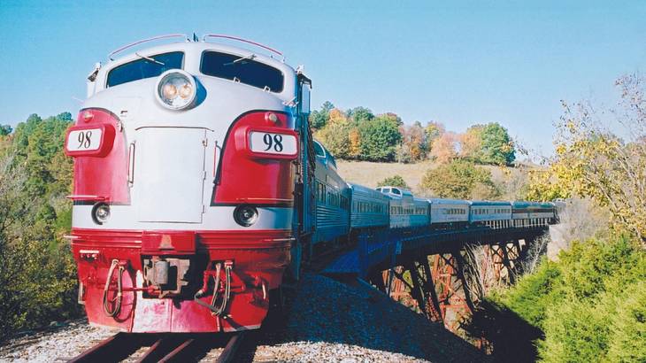 A red and white train seen from the front on a track with trees on either side