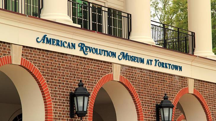 Blue text of "American Revolution Museum at Yorktown" on a building with arches Blue text of "American Revolution Museum at Yorktown" on a building with arches