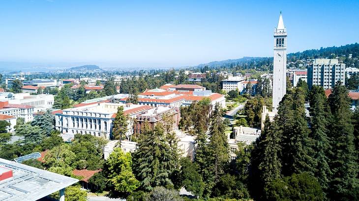 A view over a town with trees, white buildings, and a white tower A view over a town with trees, white buildings, and a white tower