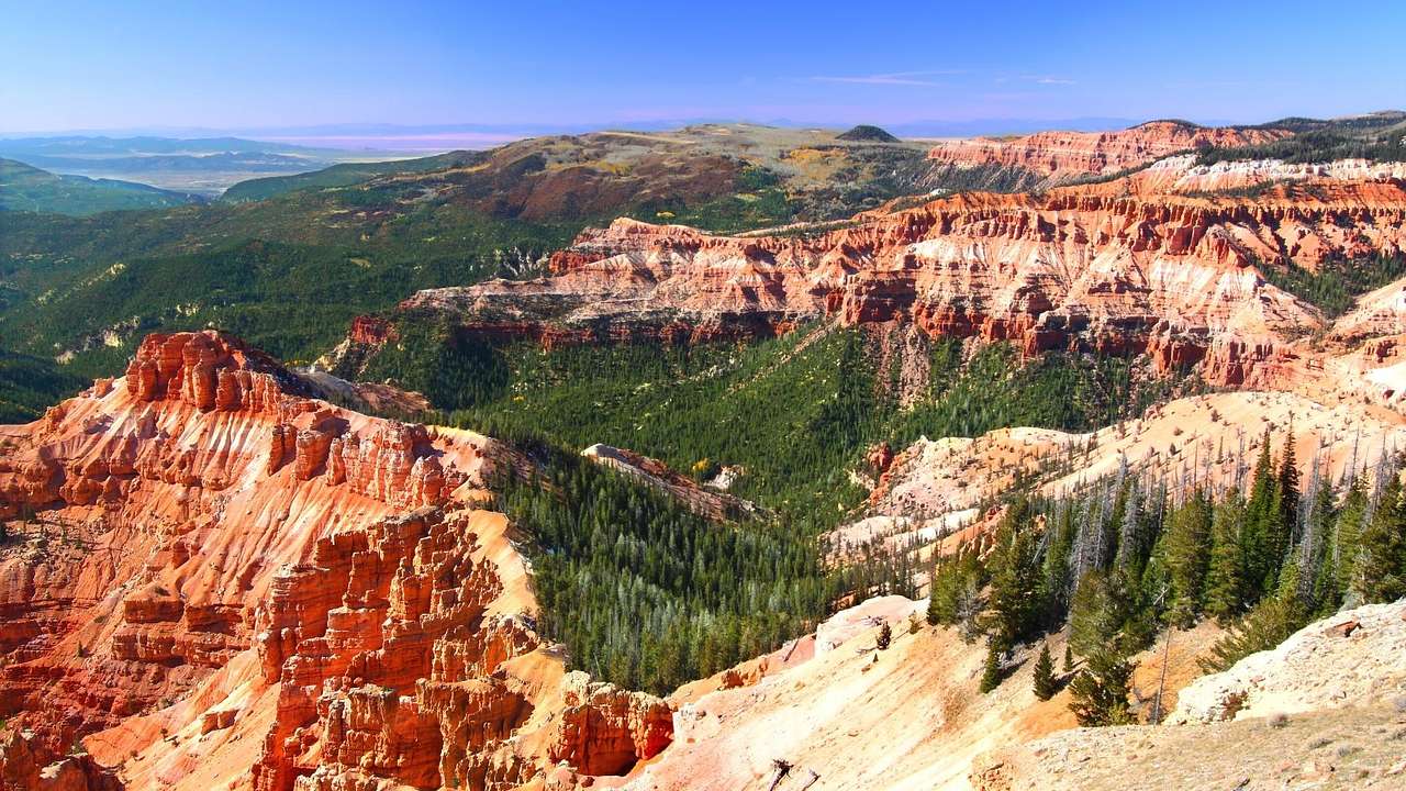 Red rock cliffs covered in greenery under a purple-blue sky
