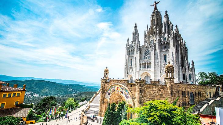 A Neo-Gothic church with a bronze statue on top, overlooking greenery on a nice day