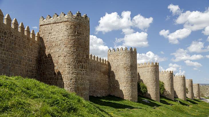 Medieval stone wall and watch towers with a partly cloudy sky in the background