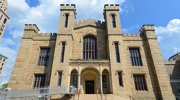 Looking up at a building styled like a gothic castle against a sky with clouds