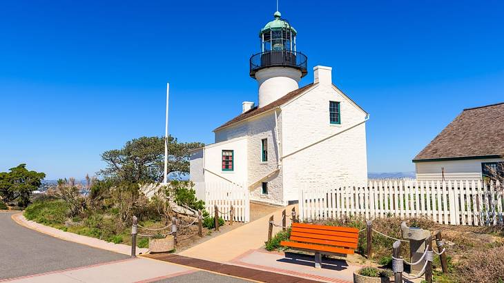 A small white building with a lighthouse tower next to a path under a blue sky
