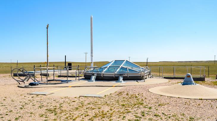 A glass viewing enclosure in the middle of an expansive field on a clear day