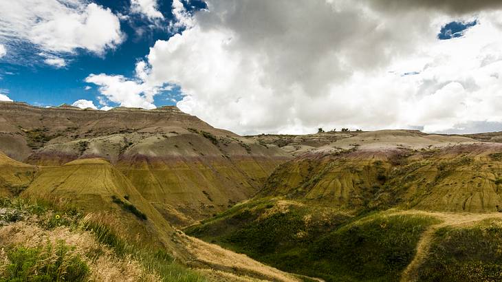 View from the top of hills in stripes of yellow, orange, and beige on a cloudy day